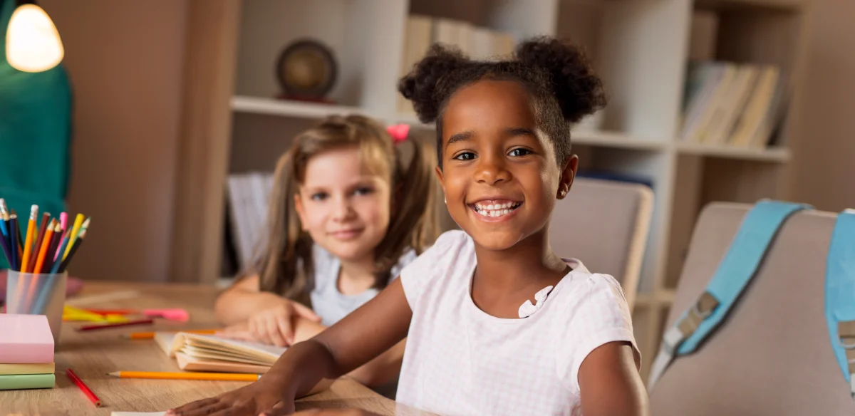 Elementary school student smiling at the camera and doing homework together