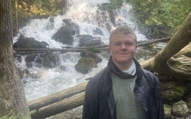 smiling boy with a waterfall in the background