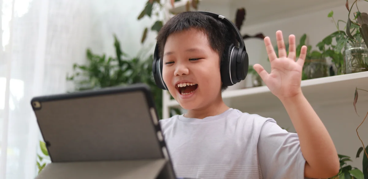 Elementary school student attending to an online class wearing a black pair of headphones