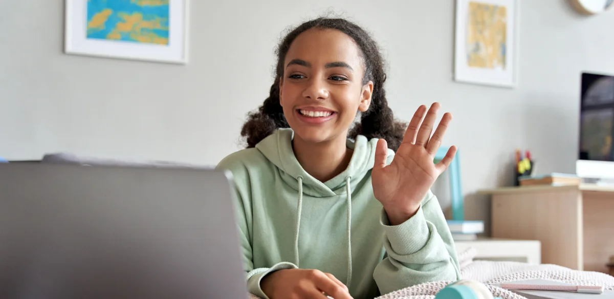 High school student attending to an online class at home wearing a light green hoodie