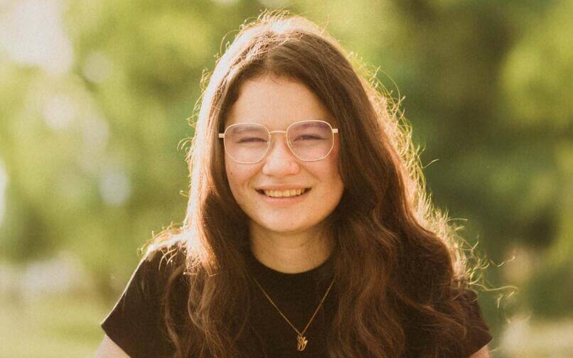girl wearing glasses smiling at a camera